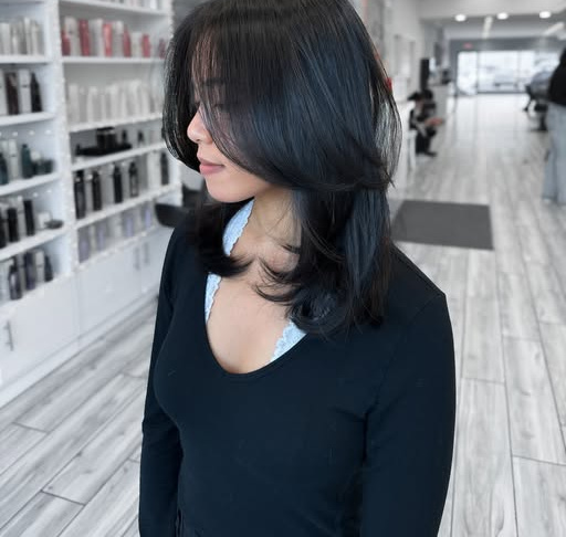 Medium-length dark layers with a curtain fringe and a face-framing layer at the jaw.